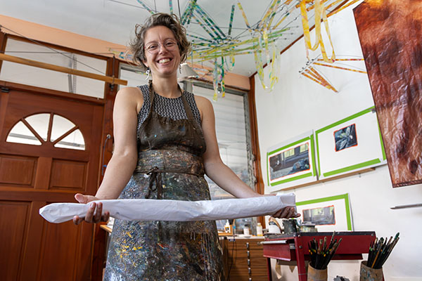 Ruth Whiting holds a painted Photon kite that is rolled up and disassembled in her studio. Kite design by Tim Elverston