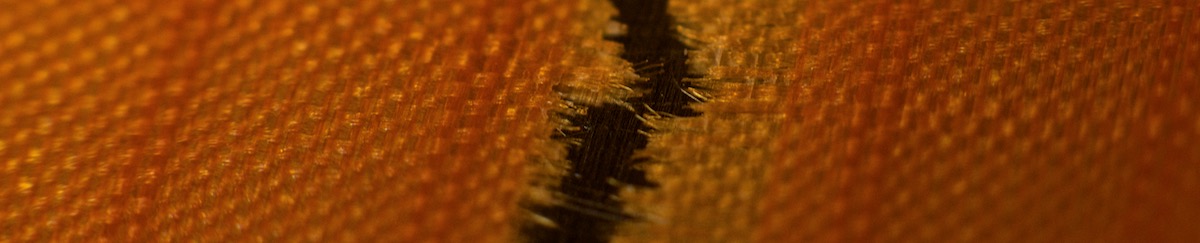 macro shot of ripped fibers of a damaged kite orange cabrinha