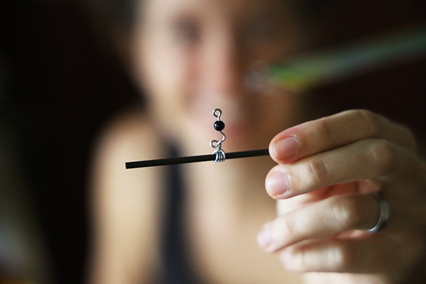 Ruth Whiting holding half of a handmade jewel-bearing swivel for a kinetic mobile