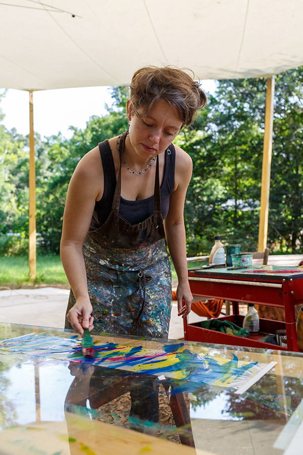 Ruth Whiting painting kinetic mobile elements outside